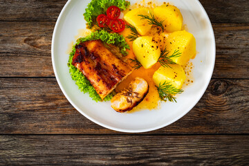 Baked rabbit saddle and boiled potatoes on wooden table