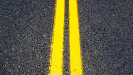 Fototapeta premium Yellow double lines mark the center of a quiet asphalt road during a sunny day
