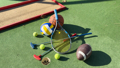 football soccer ball basketball tennis ball and racket laid on grass at sunset