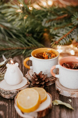 Fototapeta premium Cozy winter vibes with herbal tea, dried citrus slices, and seasonal decor – Christmas lights and fir tree branches