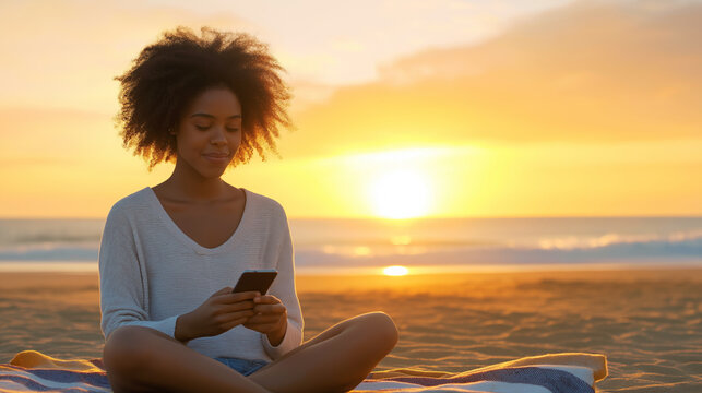 African American woman relaxing on beach blanket, scrolling smartphone during golden sunset lighting