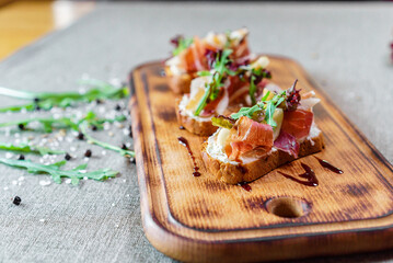 Italian bruschetta with meat, mozzarella cheese and herbs on a cutting board