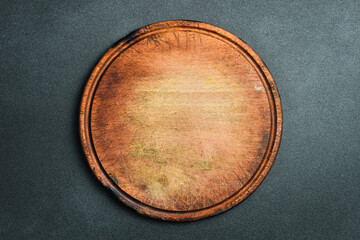 Round kitchen cutting board. On a black stone background. Top view.