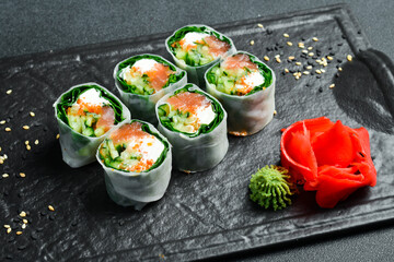 sushi rolls with salmon, kale leaves, and cream cheese. Served with wasabi sauce and pickled ginger. Japanese traditional food. Close up.