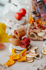 Freshly rolled, homemade fruit leather and dried fruit slices made from organic ingredients are displayed on a rustic table