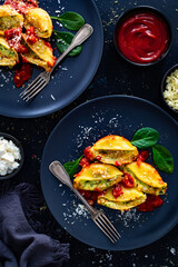 Pasta shells stuffed with cheese and spinach with tomato sauce on black table