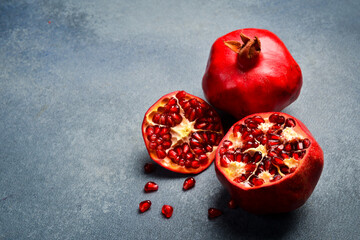 Close up. Sliced ​​ripe red pomegranate on a gray concrete background. Top view.