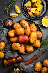 Raw organic potatoes, rosemary, oil and spices. Cooking background. On a gray stone kitchen table.