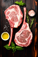 Raw Aged Tomahawk Steak with Spices and Rosemary Ready to Cook. On wooden background, top view.