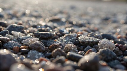 A macro image of freshly laid gravel with grains of stone reflecting light like miniature jewels. In the foreground a thin layer of fine dust clings to the larger rocks suggesting