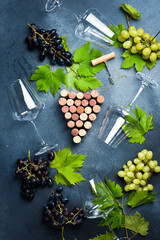 Arrangement of wine corks in the shape of a bunch of grapes and grape leaves on a stone table. Top view. Free space for text.