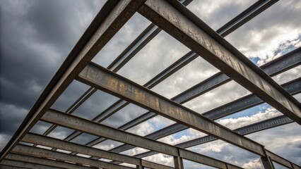 An intimate view of overlapping steel beams with their lengths creating a visually compelling pattern against the backdrop of a cloudy sky reflecting the interplay of light and