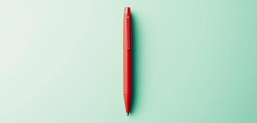 A bold red pen with a matte finish standing upright on a pastel green background, offering a minimalist design with copy space.