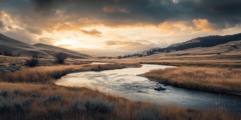 Fototapeta premium Moody Sunset Over a Serene River Flowing Through Golden Grasslands in Mountain Valley.