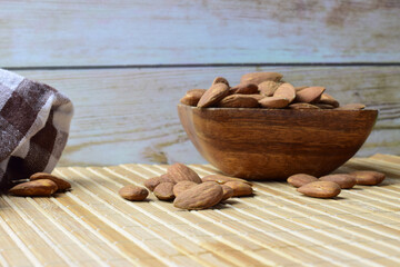 Natural almonds scattered on rustic material with a warm outline.	