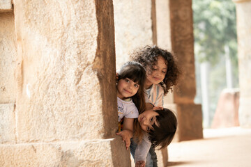 Young Children Peeping Out From Pillar