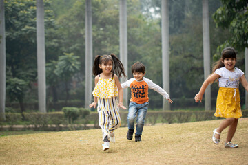 Obraz premium Three Kids Running In Garden