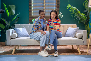 Multiracial women with smartphone in the living room. Friends having fun. High quality photo