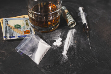 White narcotic pills, an alcoholic drink in a glass, a syringe with a dose of heroin, a line of...