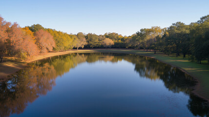 湖面に映る紅葉と岸辺の落ち葉が彩る秋の風景