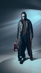 Vampire stands confidently in full leather attire holding cane in hand and bag. with a dim...