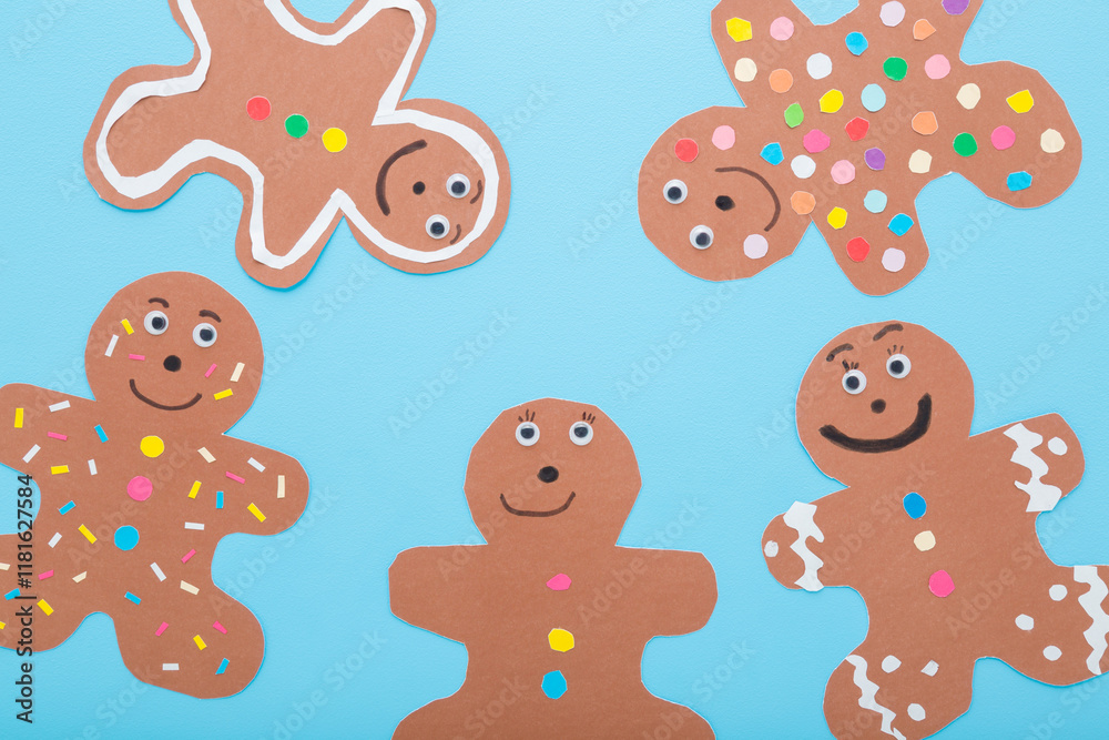Wall mural brown gingerbread man shapes with colorful pattern from application paper on light blue table backgr