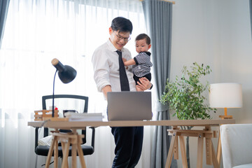 Fototapeta premium Father works at home while holding his baby in a bright and cozy office space