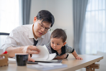Father and child enjoy quality time together while reading at a home office in daylight