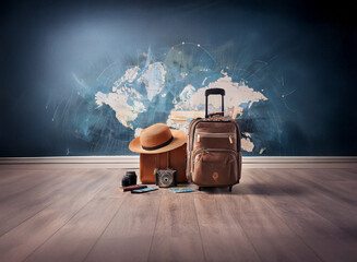 A brown suitcase and hat sit on a wooden floor against a wall depicting a world map.  Ready for adventure and exploration.