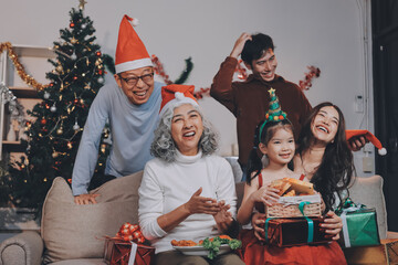 Portrait of Asian family exchanging presents during christmas at home. Attractive happy people holding gift box, celebrate holiday thanksgiving, xmas eve tradition in living room in house together.