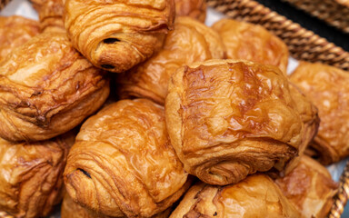 Chocolate croissant, chocolatine pastry on basket in bakery shop. Chocolate bread close-up. Pain au chocolate.