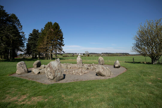 Exploring the ancient standing stones of Cullerlie in Scotland surrounded by lush greenery and clear blue skies