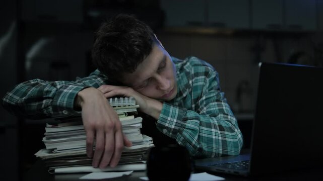 Boring tired young student or freelancer falling asleep during study or work at home workplace at late night. Man exhausted from remote distance work or education and hard program indoors