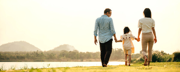 A young Asian couple walking in a green park on a beautiful spring morning, enjoying the fresh air and each other's company, Family funny day, back view
