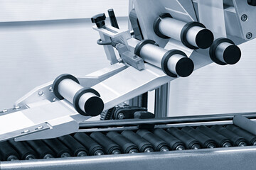 Fragment of the conveyor of sticking labeling machine. Abstract industrial background.