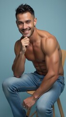 Obraz premium A muscular man with a charming smile sits casually on a wooden chair, showcasing his fit physique against a soft blue background. His relaxed pose and engaging expression radiate confidence and
