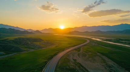 A scenic road winding through lush green fields at sunset