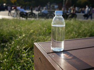 公園のベンチに置かれた水入りのペットボトル