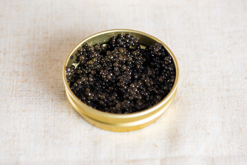 Black caviar in the gold jar on the table. Sturgeon caviar.