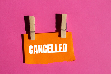 Cancelled message written on ripped torn orange paper piece with pink background. Conceptual...