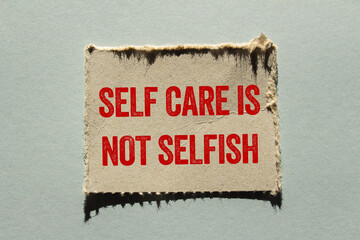 Self care is not selfish message written on ripped torn paper piece on gray background. Conceptual...