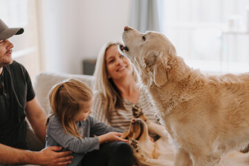 Happy family snuggles on the couch with their pets.