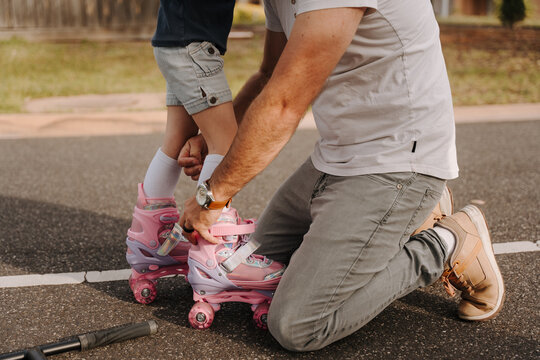 Dad helping daughter get into her roller skates