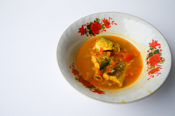 Fresh fish soup in a simple basin, served with spices and sliced chili