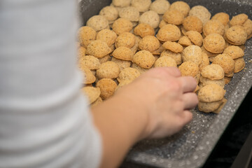 A woman's hand compares baked cookies on a baking sheet.
