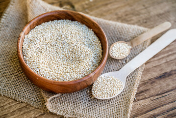 White quinoa seeds in a wooden bowl 