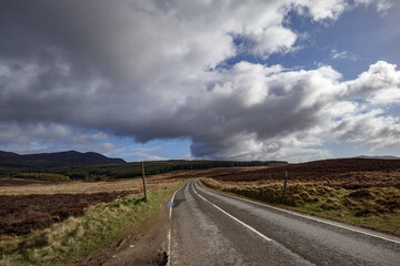 Scenic winding road through the Scottish Highlands under a dramatic sky in late afternoon