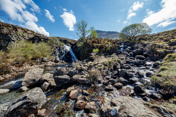 Waterfall cascading through rocky terrain in Isle of Skye Scotland under a clear blue sky