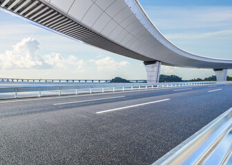 Asphalt road and bridge with beautiful coastline scenery under blue sky. Outdoor road background.