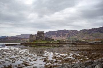 Historic castle surrounded by tidal flats in Scotland’s scenic landscape under an overcast sky